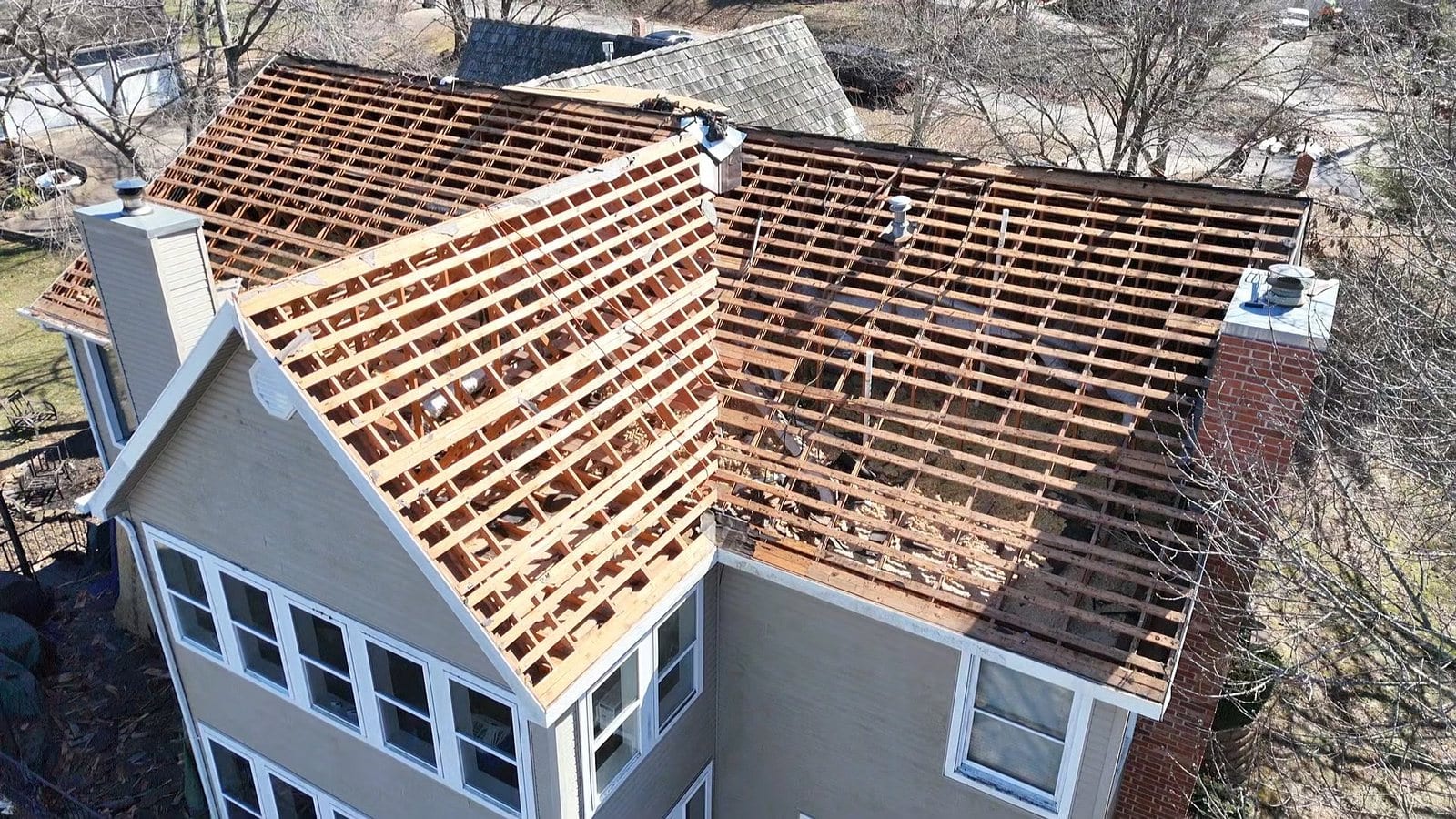 Roof stripped to the rafters with replacement decking going down over a two-storey home